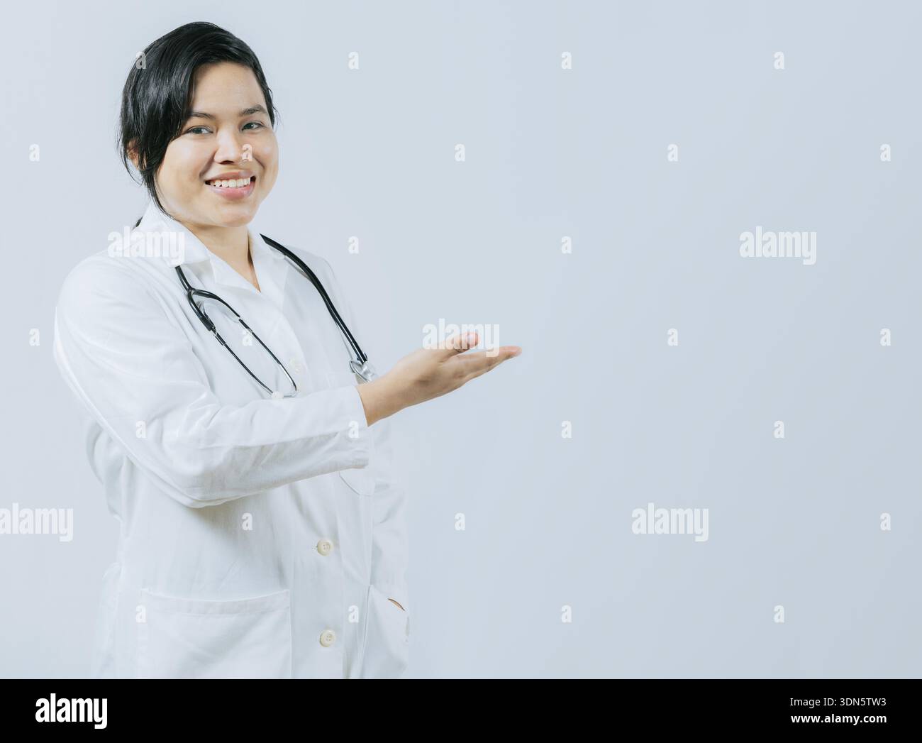 Jeune médecin asiatique présentant quelque chose d'isolé. Médecin féminin asiatique souriant montrant un espace vide Banque D'Images