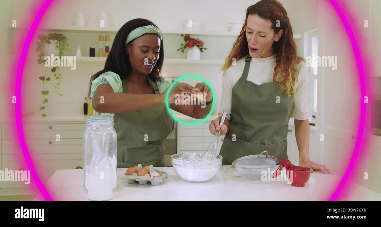 Paire de femmes préparant la pâte dans la cuisine blanche, portant des tabliers d'olive, en utilisant bol, fouet, oeufs, pot Banque D'Images
