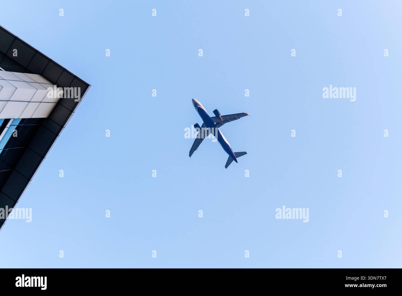 Avion volant au-dessus des gratte-ciel d'affaires bâtissant sur le ciel bleu Banque D'Images