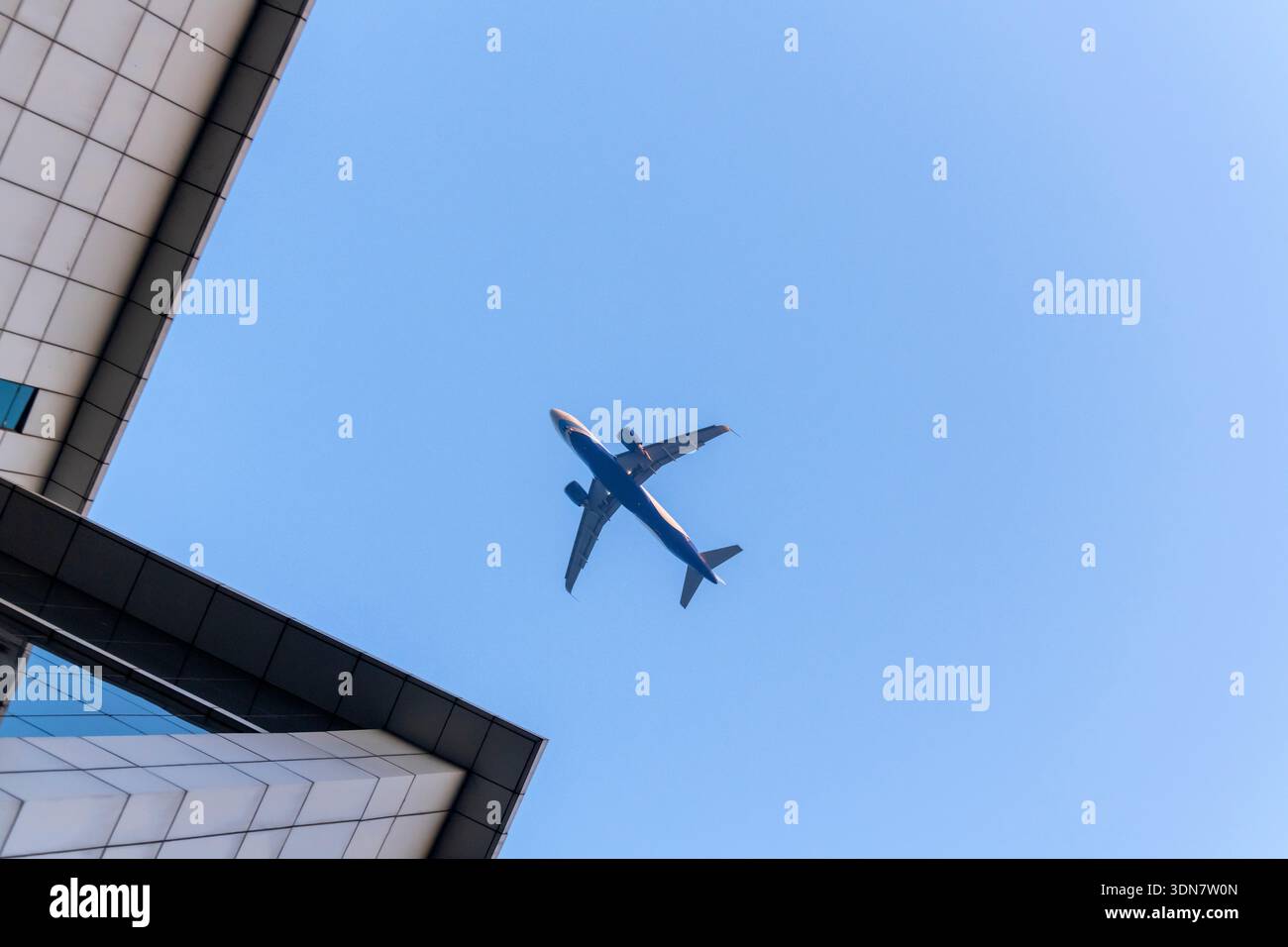 Avion volant au-dessus des gratte-ciel d'affaires bâtissant sur le ciel bleu Banque D'Images