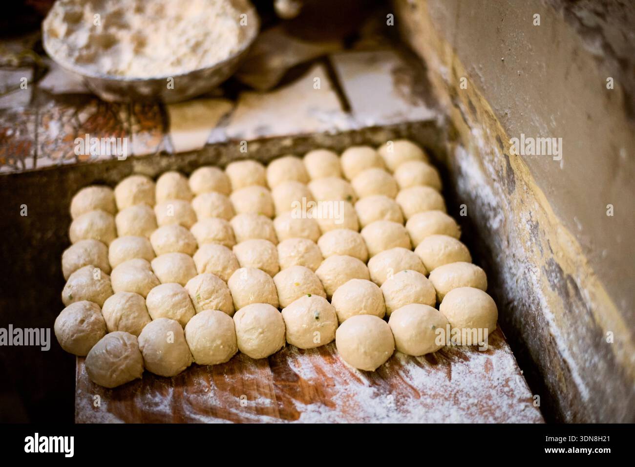 Boules de pâte soigneusement disposées sur une surface en bois saupoudrée de farine prête à être cuite. Kigali, Rwanda Banque D'Images