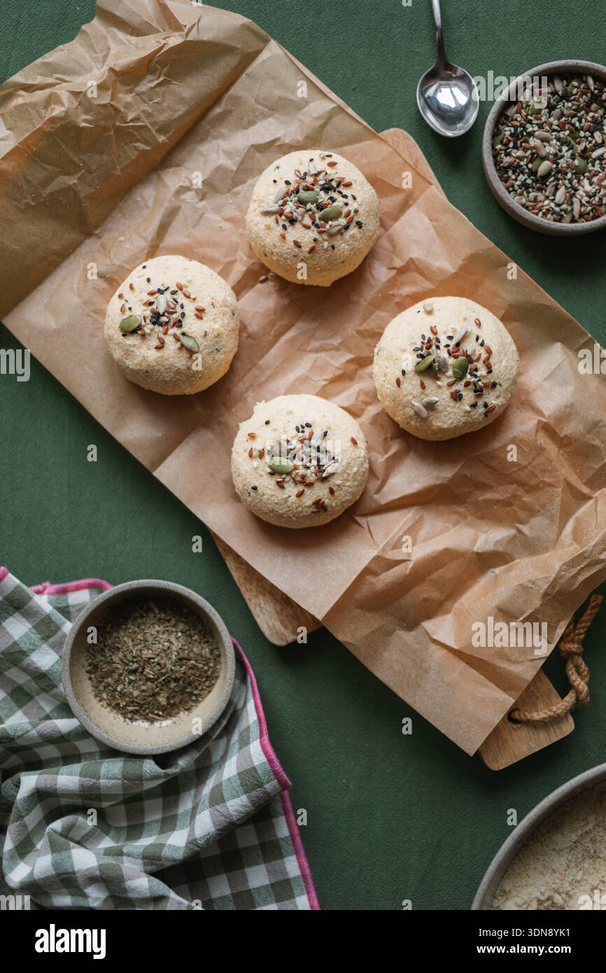 Vue de dessus des petits pains keto Low Carb faits avec ricotta, amande et farine de noix de coco et des œufs surmontés de graines assorties sur une table avec des ingrédients Banque D'Images