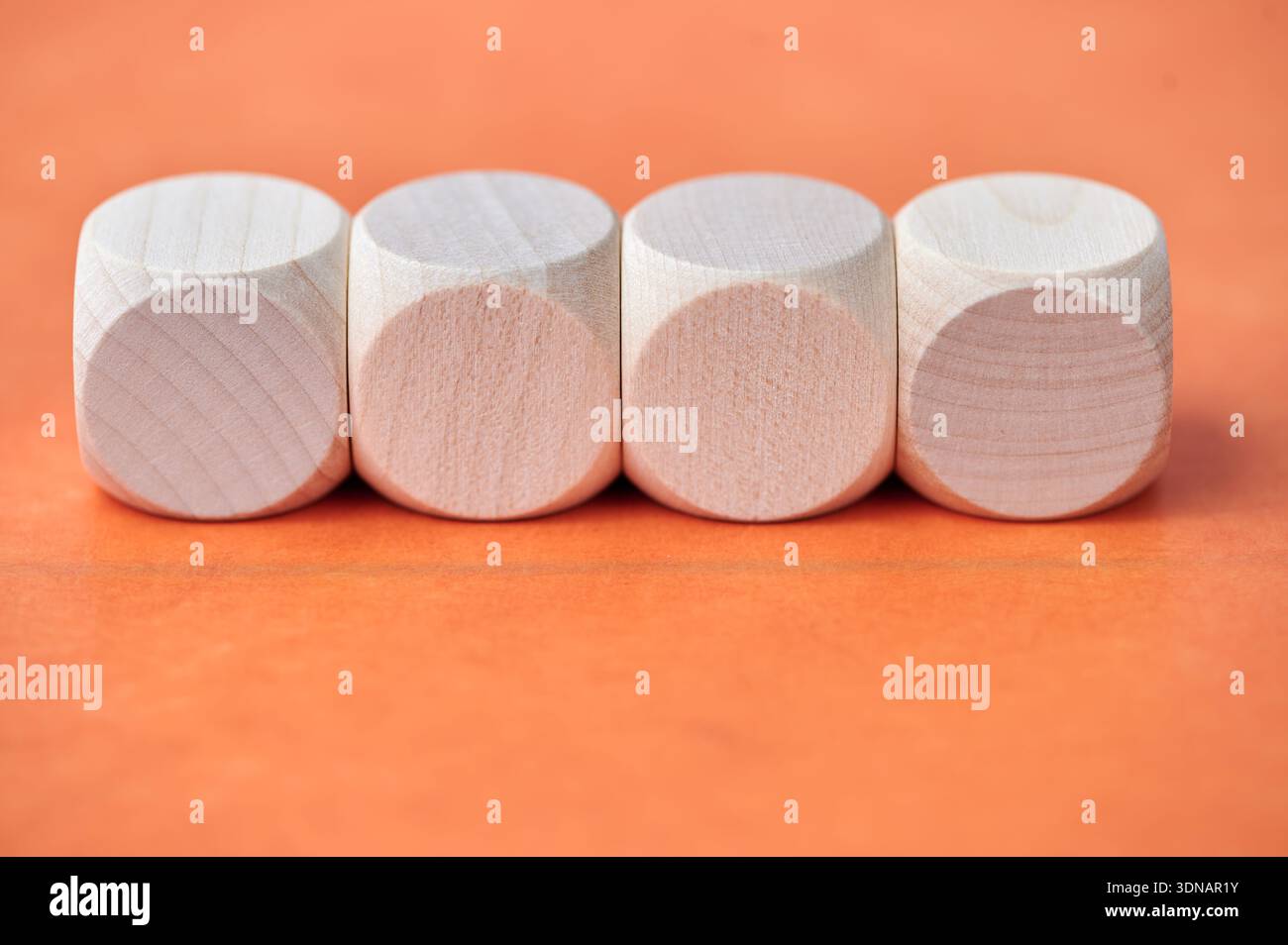 Quatre blocs de bois cylindriques sont placés côte à côte sur orange. Banque D'Images