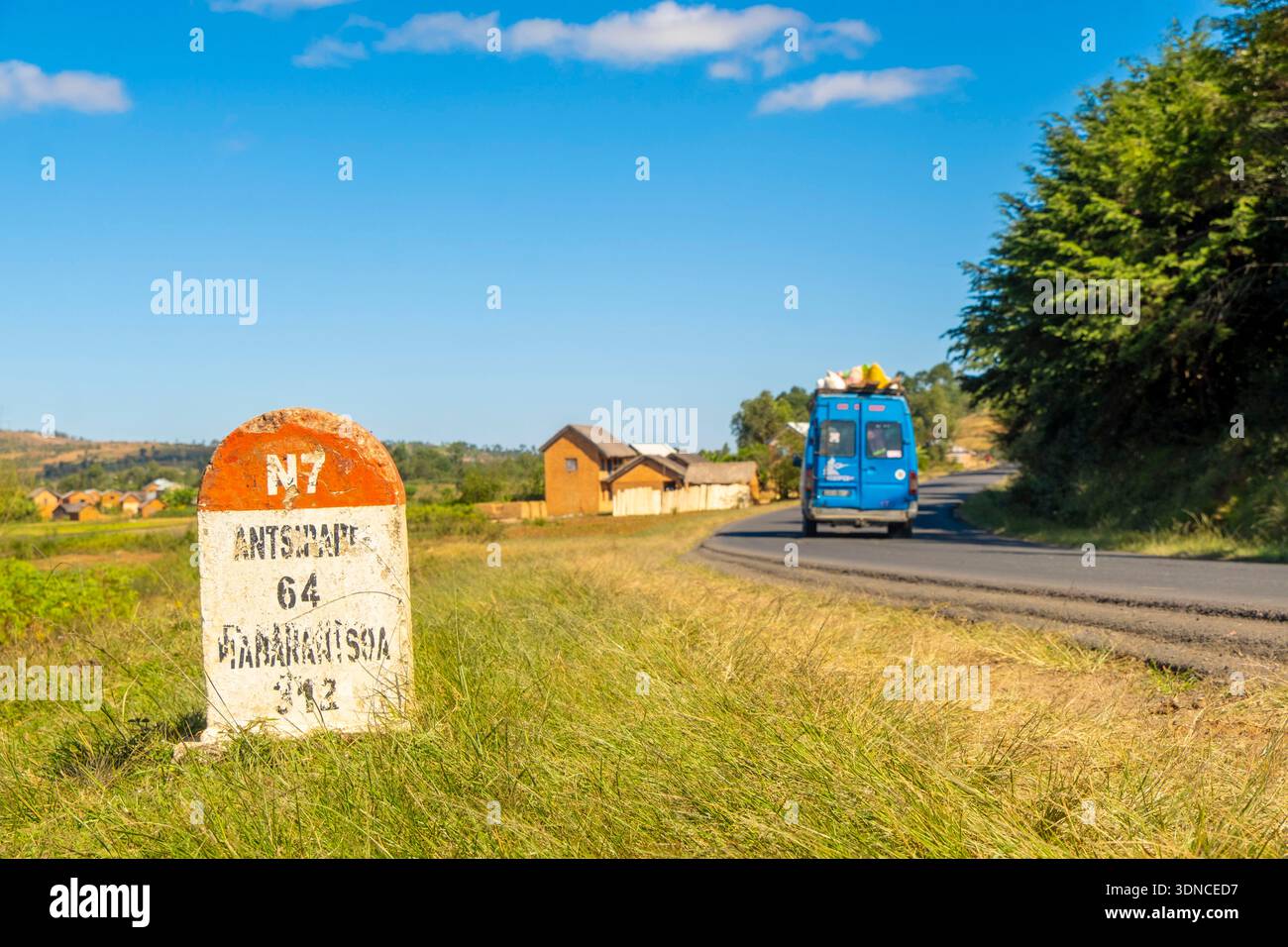 Madagascar, région de Vakinankaratra, route nationale 7 ou RN7, près d'Antsirabe à 64 km au Nord, borne kilométrique et passage d'un taxi collectif Banque D'Images