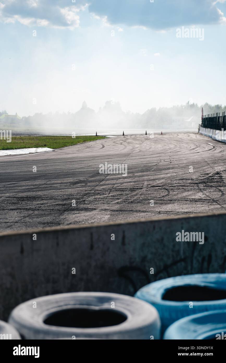 Virement de course vide avec marques de pneu et fumée persistante. Circuit asphalté après une séance. La surface marquée de traînées de pneu et d'un épais voile de fumée blanche Banque D'Images