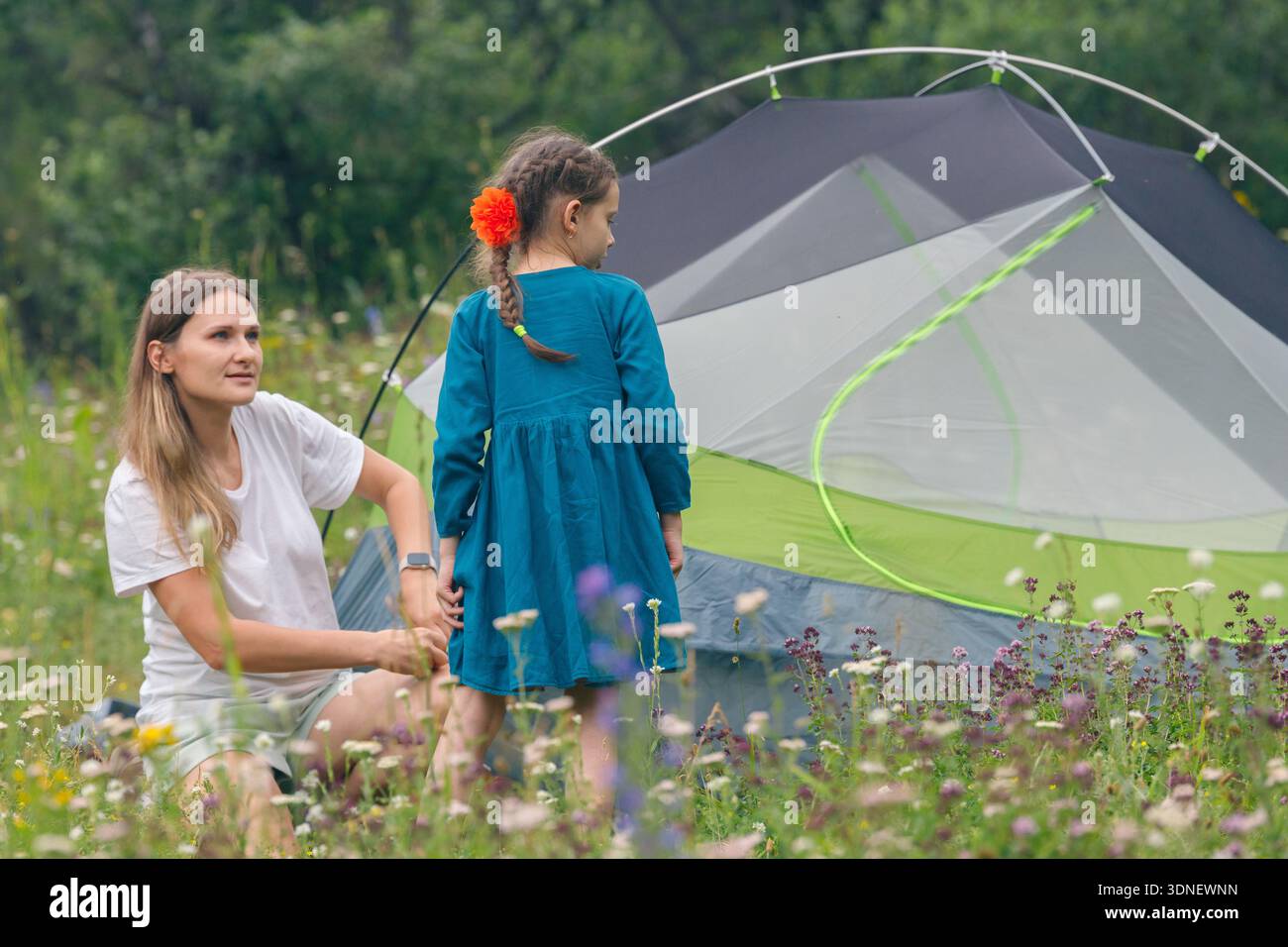 Une mère et sa fille profitent d'un voyage de camping ensemble dans une belle prairie panoramique entourée par la nature Banque D'Images