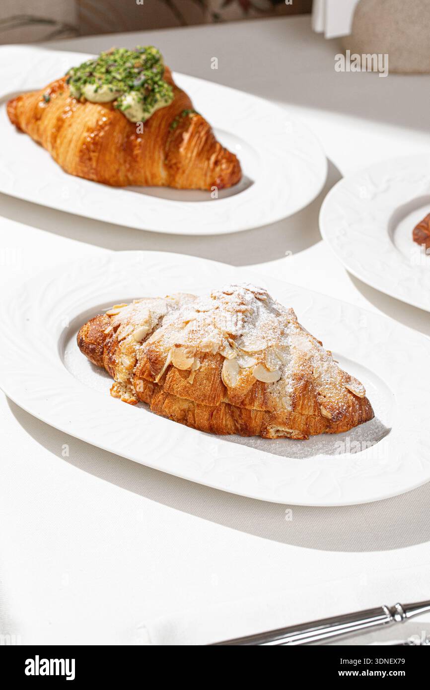 Croissant aux amandes et croissant à la pistache sur assiettes Banque D'Images