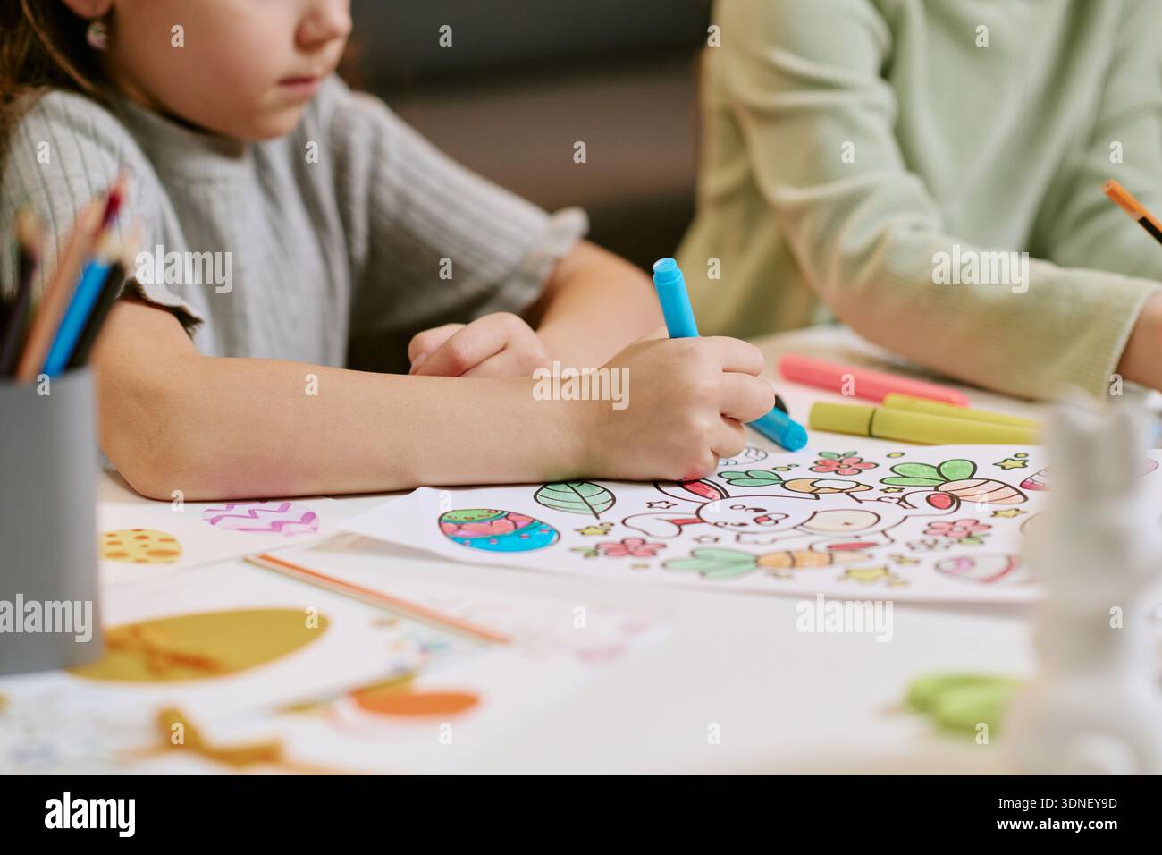 Fille dessinant image colorée tout en étant assis à table à l'intérieur Banque D'Images