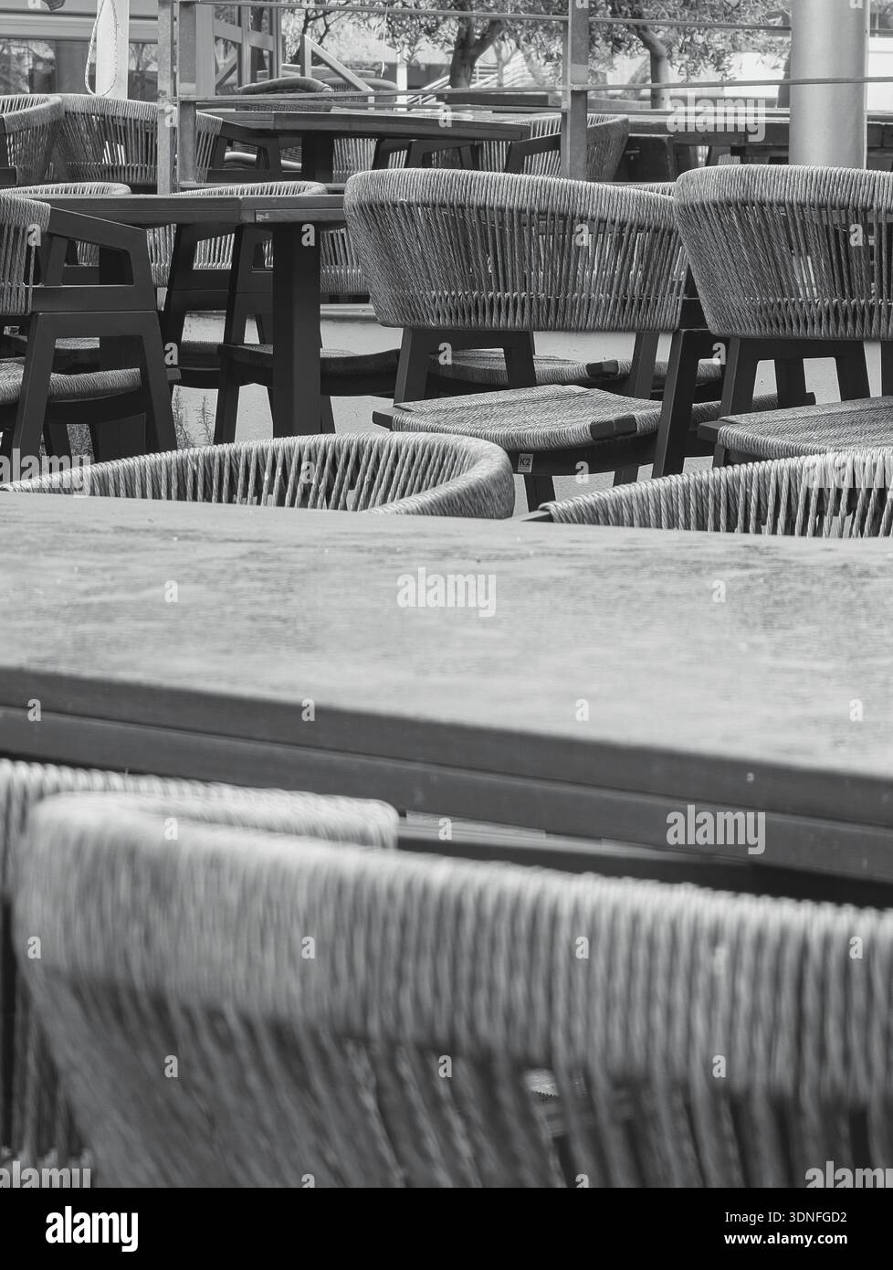 Des chaises vintage silencieuses jettent des ombres sur la terrasse ouverte remplie de rythme architectural et de profondeur Banque D'Images
