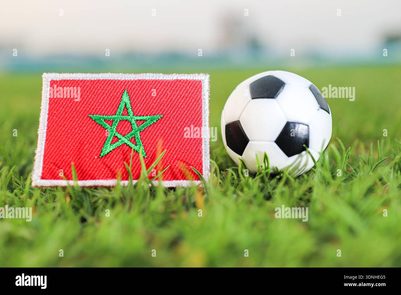 Drapeau marocain et ballon de football sur herbe verte. Représentation symbolique de la fierté du football nord-africain et des matchs sportifs internationaux. Banque D'Images
