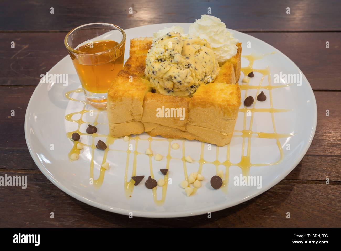 Toast au miel sur plat blanc. Nappé de crème fouettée et glacée. dessert sucré. Banque D'Images