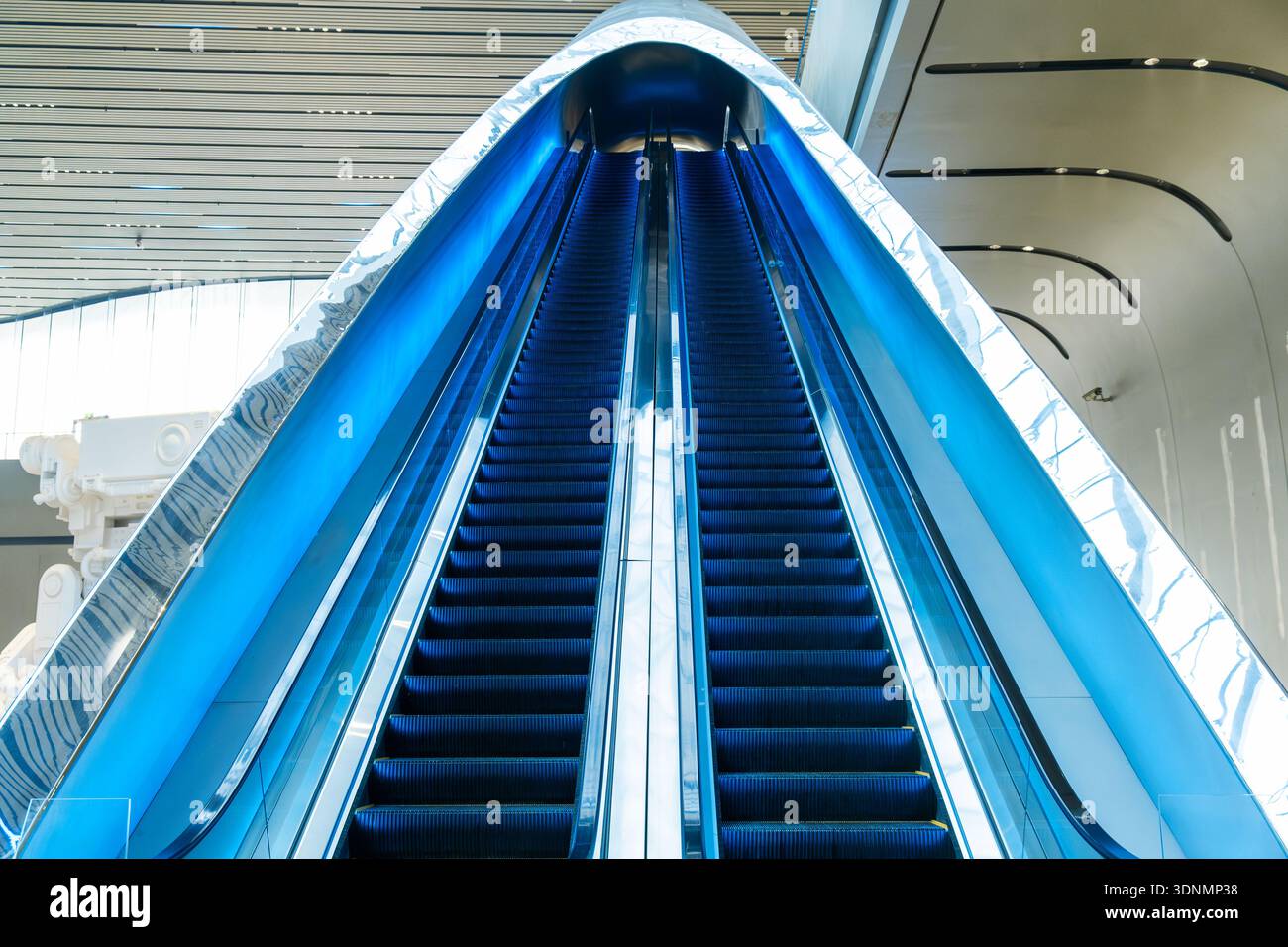 Escalators bleus modernes à l'intérieur d'un bâtiment futuriste à l'architecture courbe et aux surfaces brillantes avec une perspective symétrique dans la ville de Chengdu, en Chine Banque D'Images