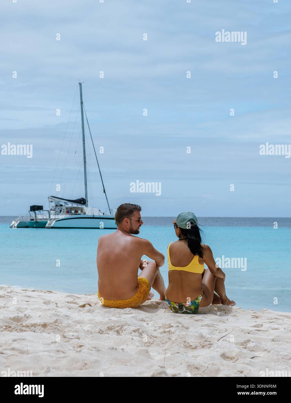 Une scène de plage sereine à Klein Curaçao met en scène un couple assis ensemble, appréciant les uns les autres compagnie. Le sable doux et les eaux turquoises limpides créent un cadre parfait pour la détente et le romantisme. Banque D'Images