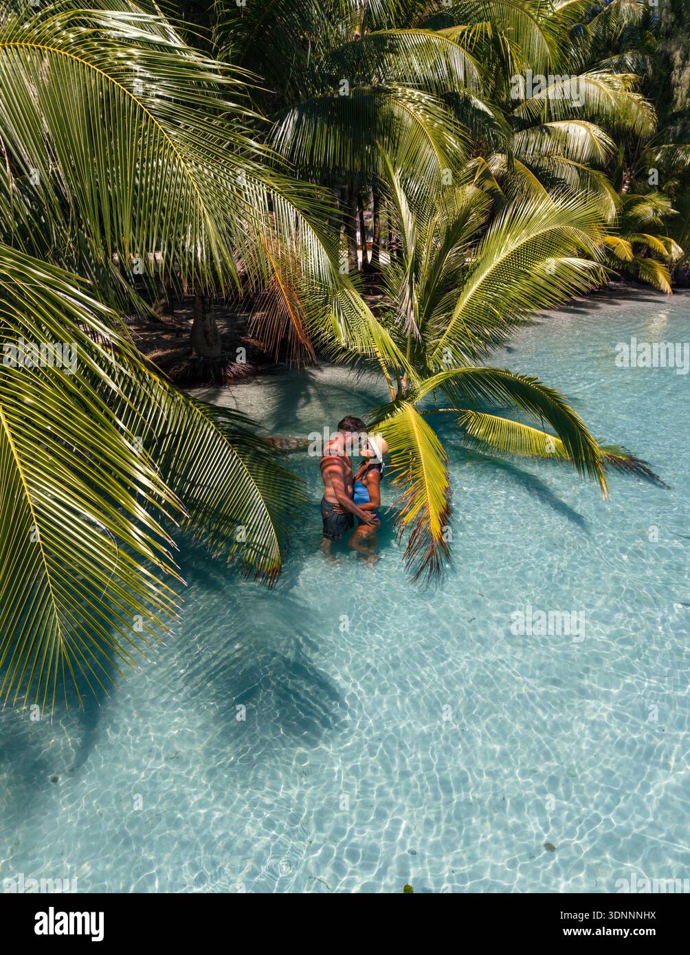 Un couple aimant profite d'un moment romantique dans les eaux sereines de la plage de Khlong Hin à Koh Kood, en Thaïlande. Les palmiers verdoyants créent une atmosphère paradisiaque tropicale. Banque D'Images