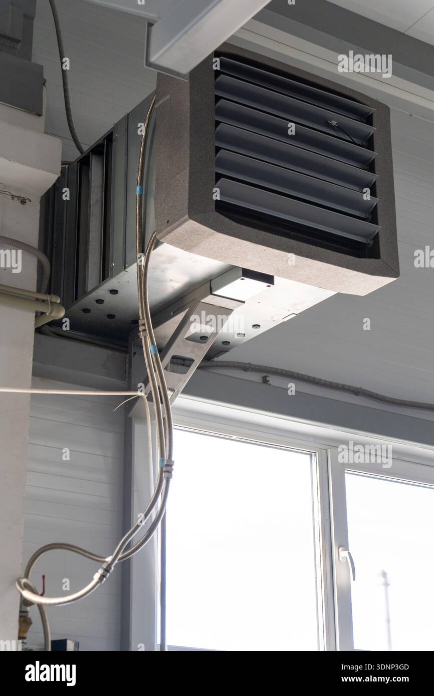 Unité de ventilation industrielle avec conduit d'air et diffuseur à persiennes monté sous le plafond. Équipement HVAC dans une usine ou un atelier pour le contrôle de la climatisation Banque D'Images