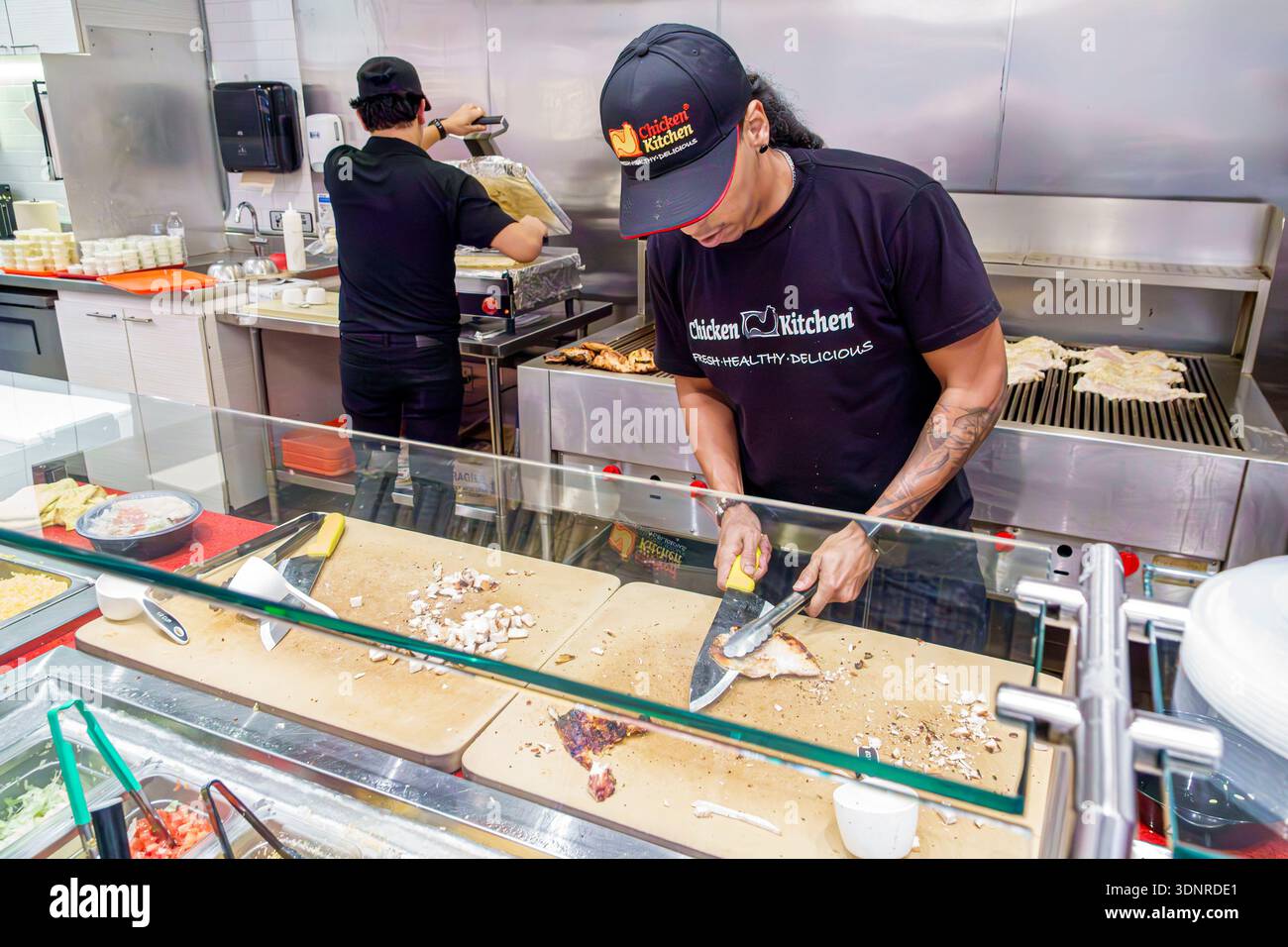 Miami Florida, South Dixie Highway US route 1, restaurant de restauration rapide Chicken Kitchen, poulet adulte employé hachant mâle, planche à découper à grand couteau, grill Banque D'Images