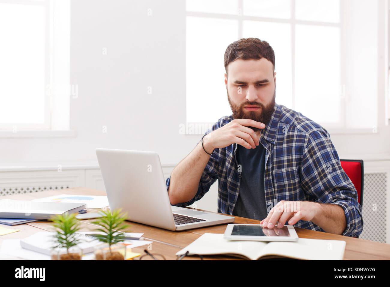 Gros plan portrait d'un jeune homme d'affaires pensif assis et utilisant un ordinateur tablette dans le bureau Banque D'Images