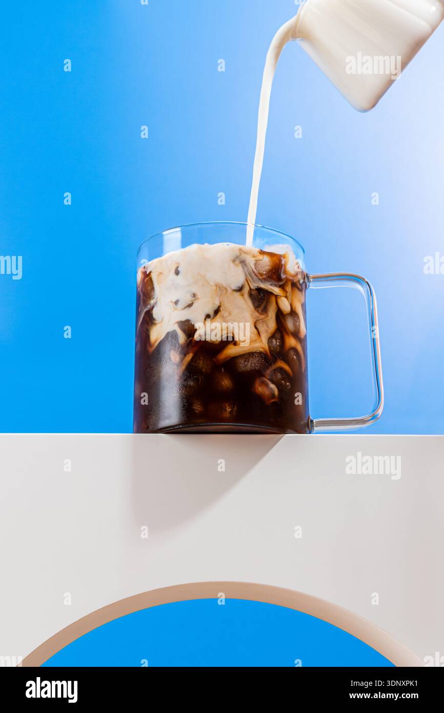 Un cliché dynamique capturant le lait crémeux versé dans un espresso glacé rafraîchissant, créant un magnifique effet tourbillonnant. Parfait pour un café sur le thème l Banque D'Images