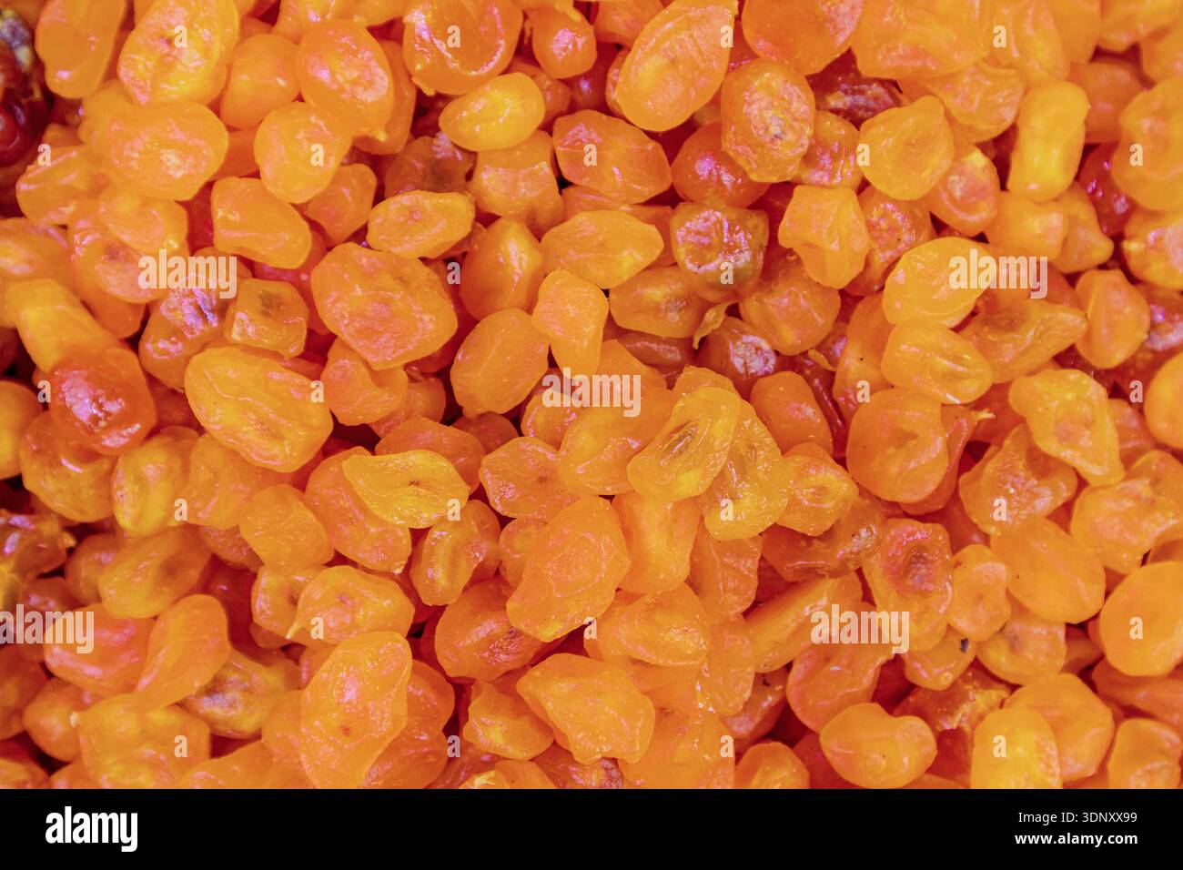 Vue de dessus d'abricots séchés orange vif formant un fond texturé. Les abricots sont dispersés étroitement, créant un visuel coloré et appétissant Banque D'Images