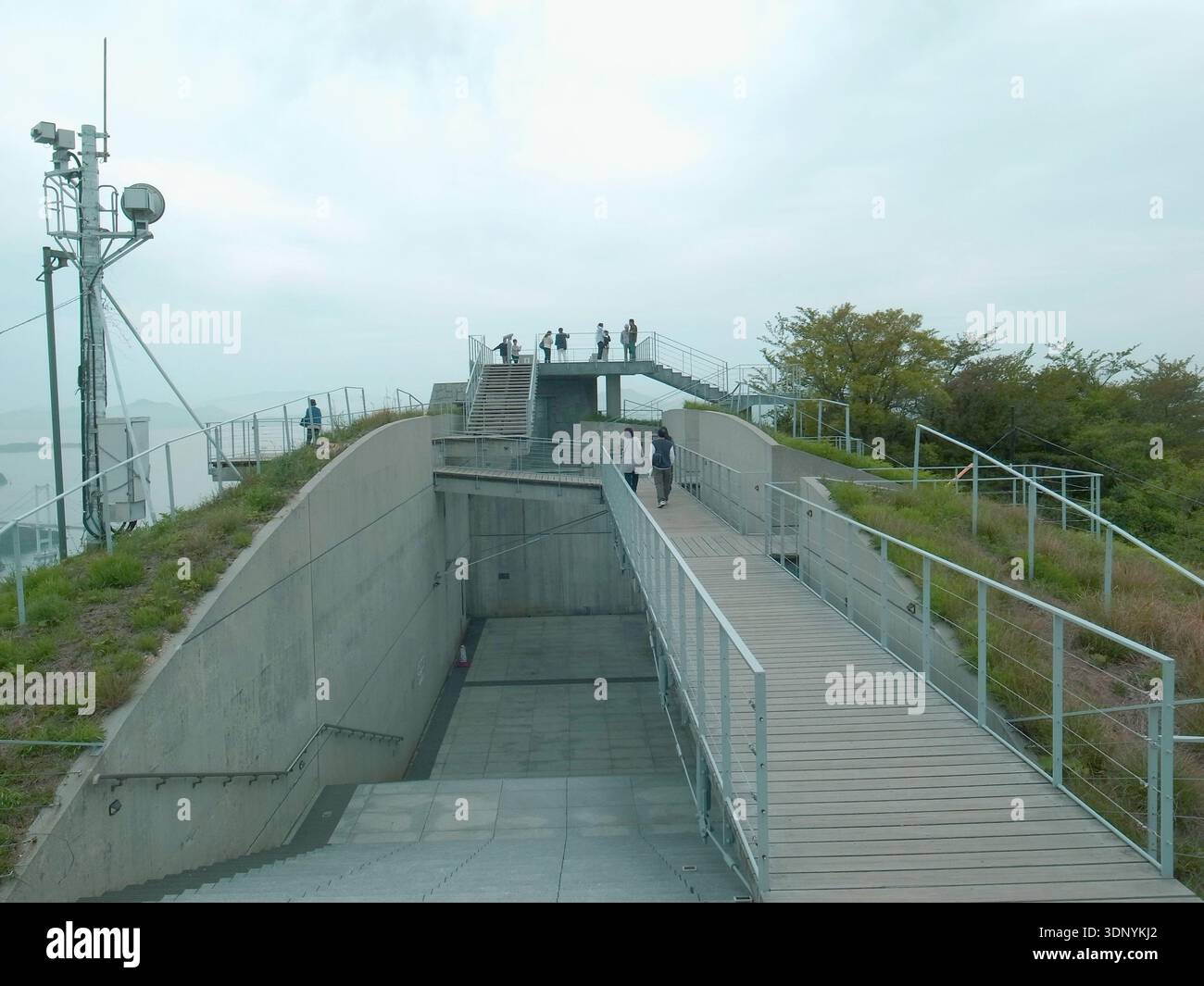 Terrasse d'observation en béton moderne avec passerelle en bois surélevée et garde-corps, visiteurs sur la plate-forme sur le toit, aménagement paysager à flanc de colline verte, antennes, overca Banque D'Images