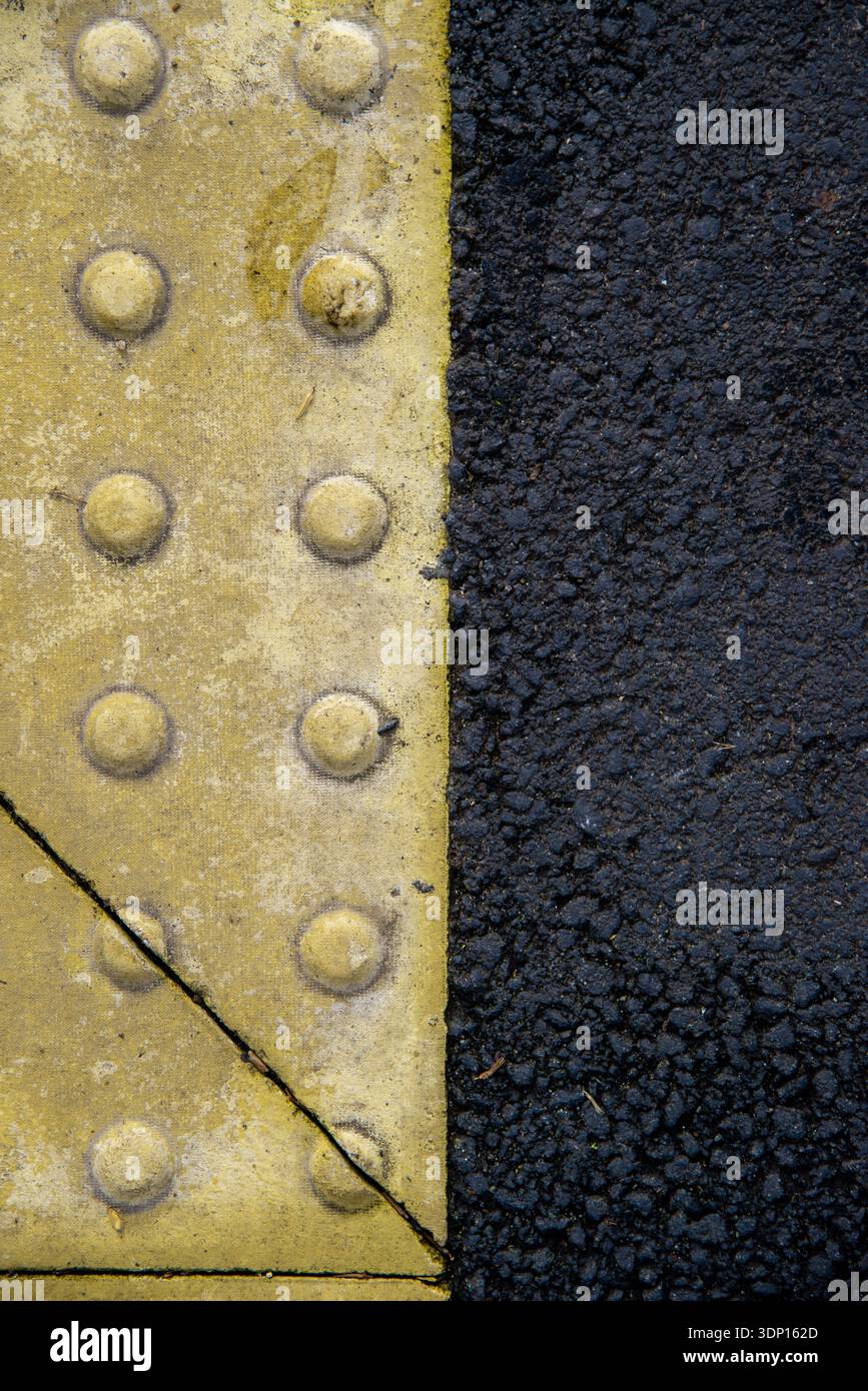 Plaque de joint de dilatation en métal jaune avec boulons en texture asphaltée Banque D'Images