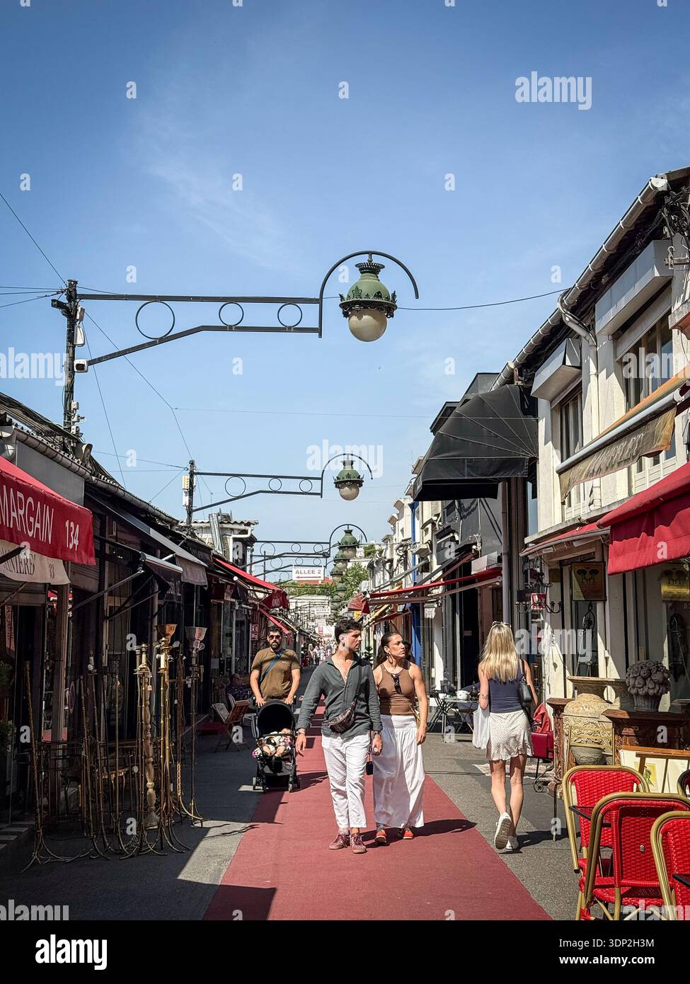 PARIS, FRANCE - 22 JUIN 2025 : les visiteurs se promènent dans la Marche Biron au marché aux puces de Saint-Ouen à Paris, France. Allée moquette rouge, rue antique Banque D'Images