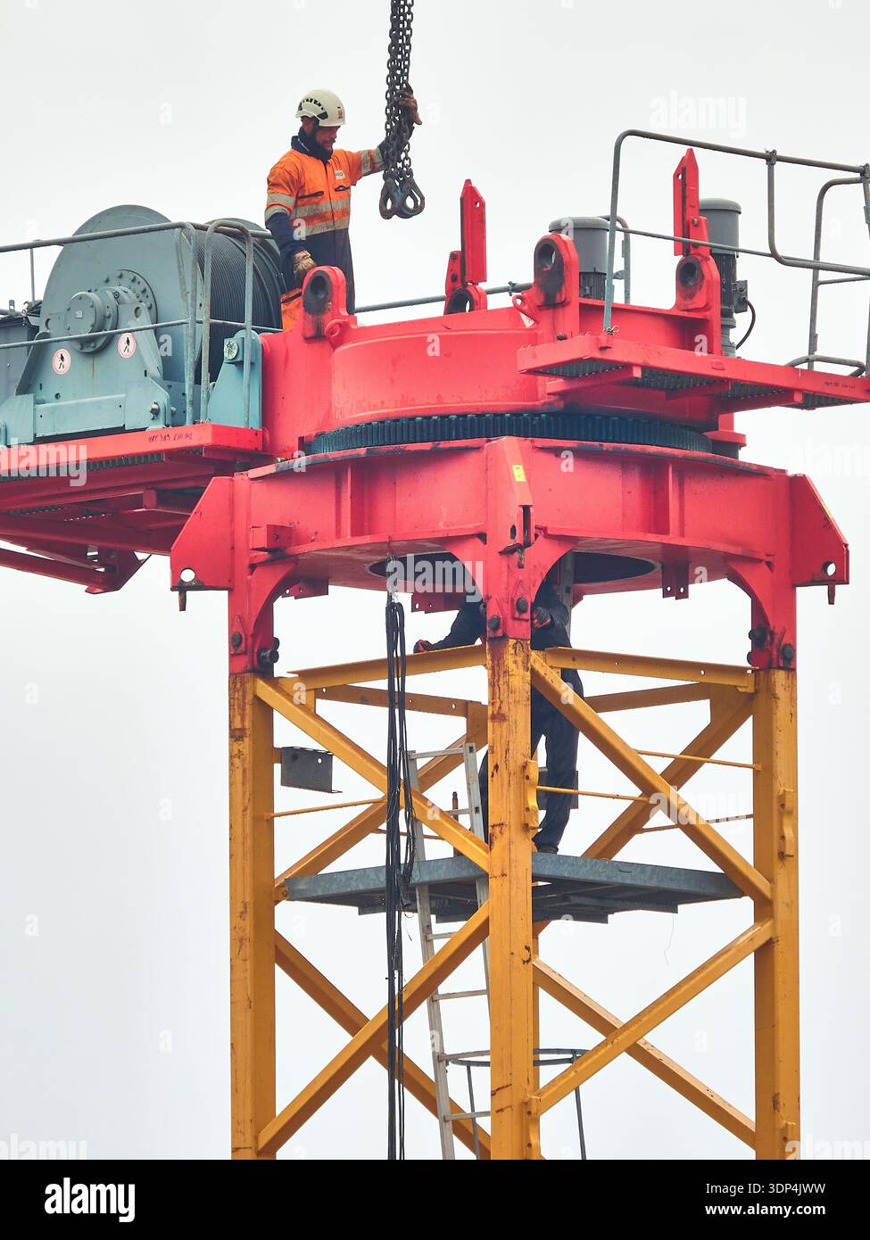 Ouvrier de construction sur grue à tour portant un équipement de sécurité en hauteur sur le site industriel Banque D'Images