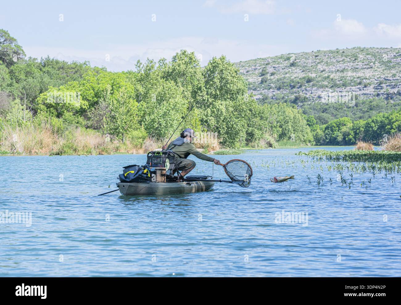 L'homme tente d'enlever le poisson du kayak Banque D'Images