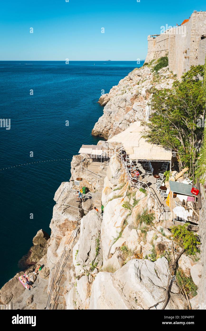 Lieu de baignade et café dans les rochers sous les murs de la ville de Dubrovnik avec vue sur la mer Méditerranée Banque D'Images