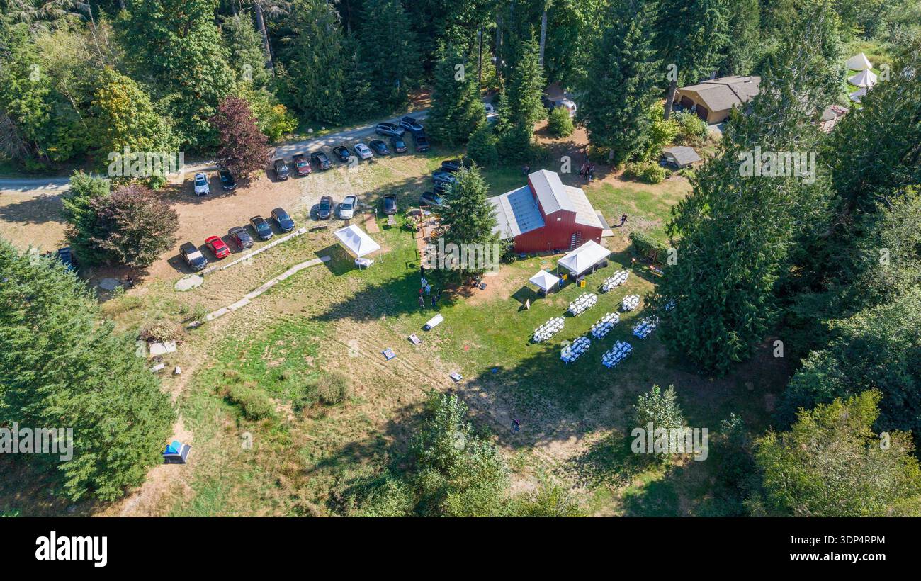 Vue aérienne d'une scène pittoresque où une grange rouge se dresse au milieu d'une végétation luxuriante, accueillant un événement en plein air, Swede Heaven, Washington, États-Unis. Banque D'Images