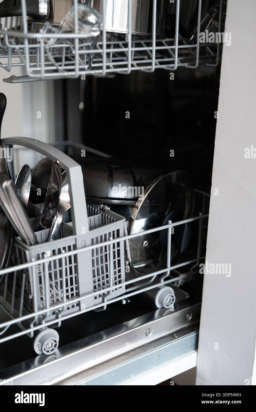 Charger un lave-vaisselle moderne avec de la vaisselle et des couverts sales dans la cuisine, préparer un cycle de nettoyage automatisé et la corvée ménagère Banque D'Images