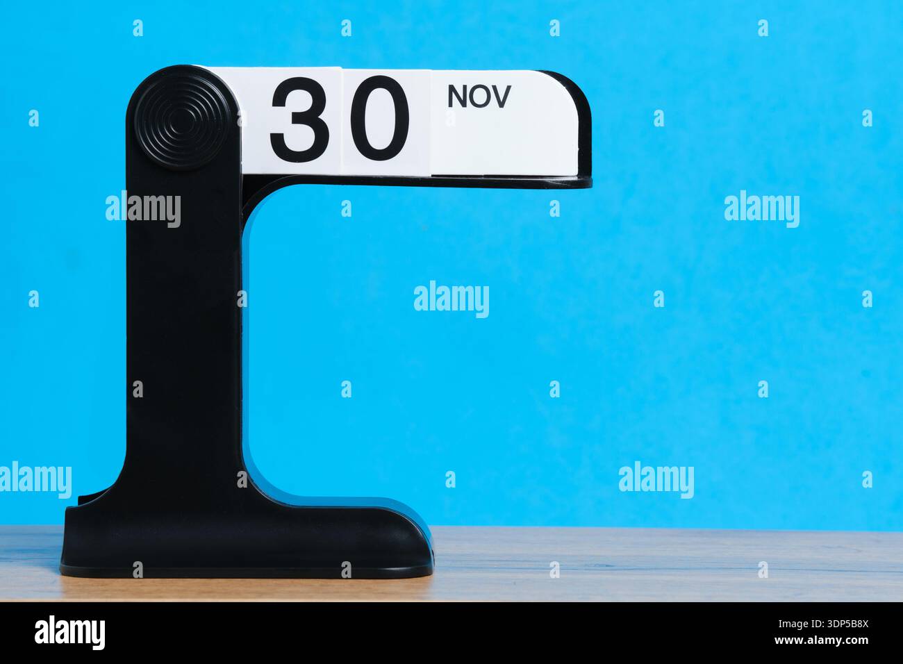 Calendrier moderne de flip montrant novembre 30 sur une table en bois avec fond bleu vif Banque D'Images