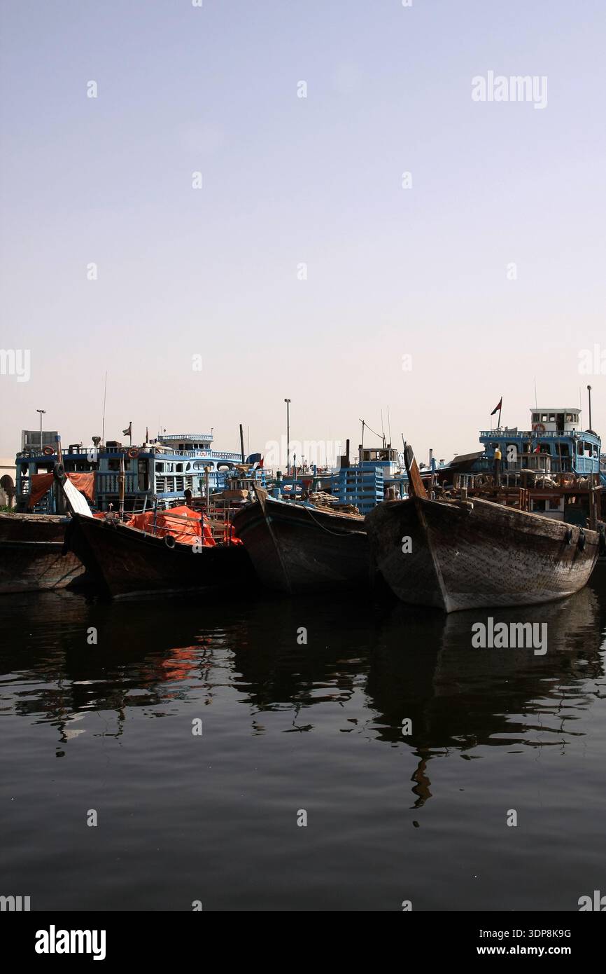 Bateaux de charge traditionnels en bois Dhow regroupés et amarrés au Dubai Creek avec des reflets d'eau calmeBateaux de charge traditionnels en bois Dhow regroupés Banque D'Images