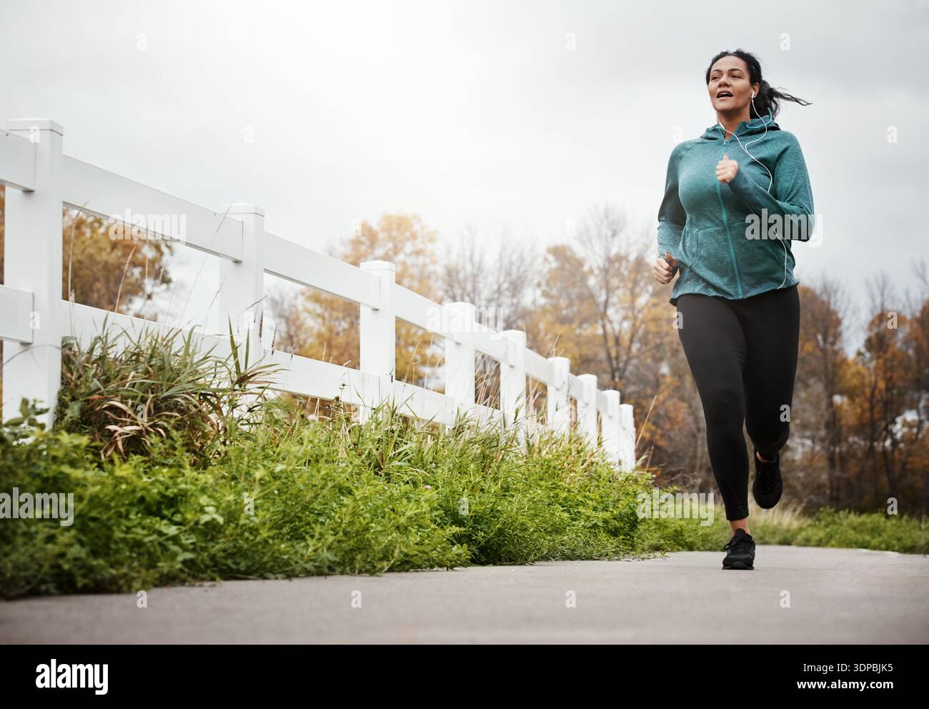 Femme, course et streaming au parc avec écouteurs avec entraînement cardio, espace et sourire avec audio. Personne, entraînement et coureur avec exercice, bas Banque D'Images