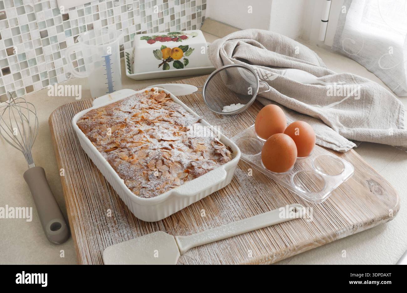 Gâteau éponge avec pétales, flocons d'amande et sucre en poudre. Dessert et fête à la maison. Cuisine et passe-temps. Banque D'Images