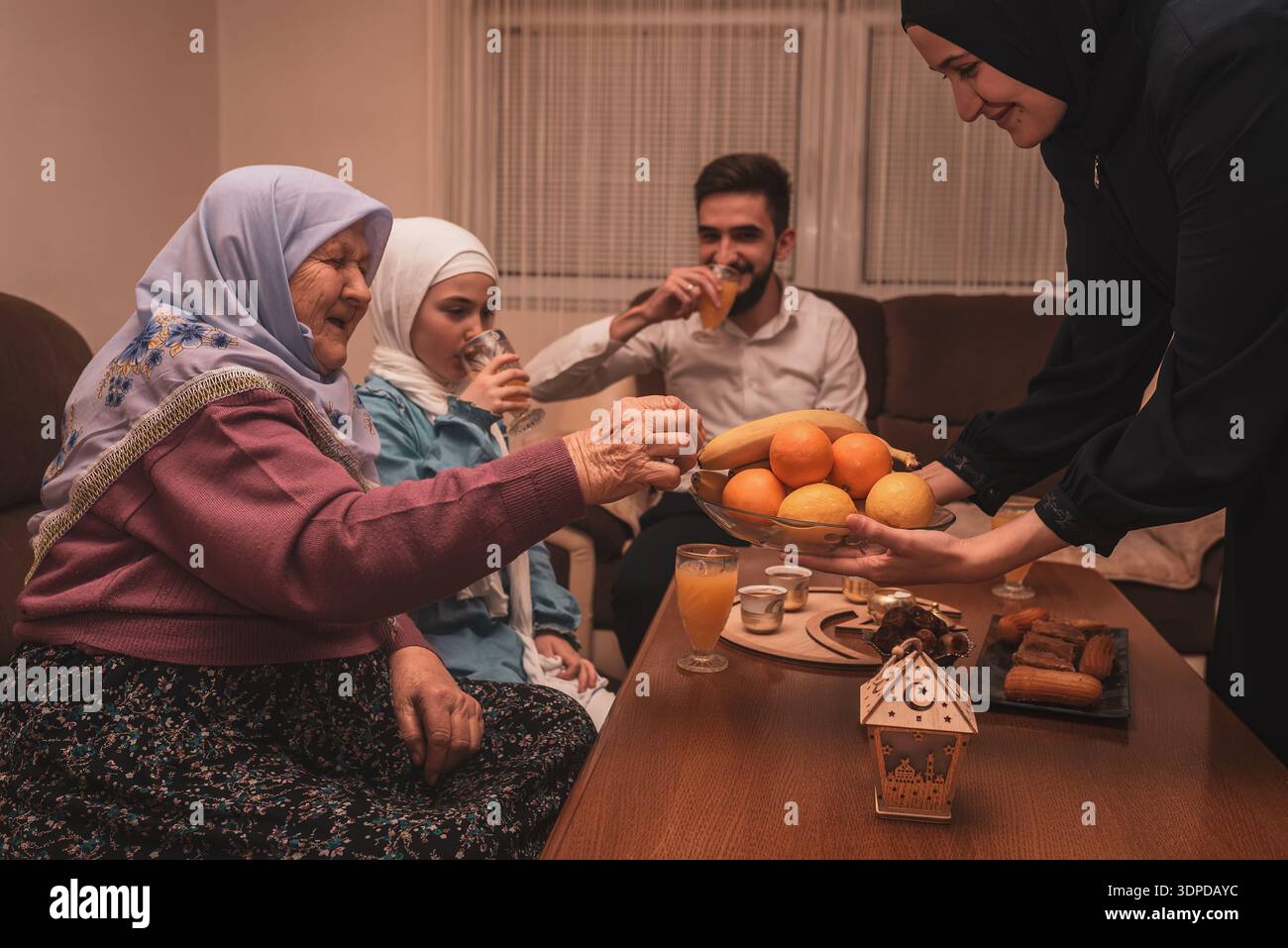 Heureuse famille musulmane ayant dîner iftar pendant le Ramadan table à manger à la maison, partageant la nourriture et souriant ensemble. Banque D'Images