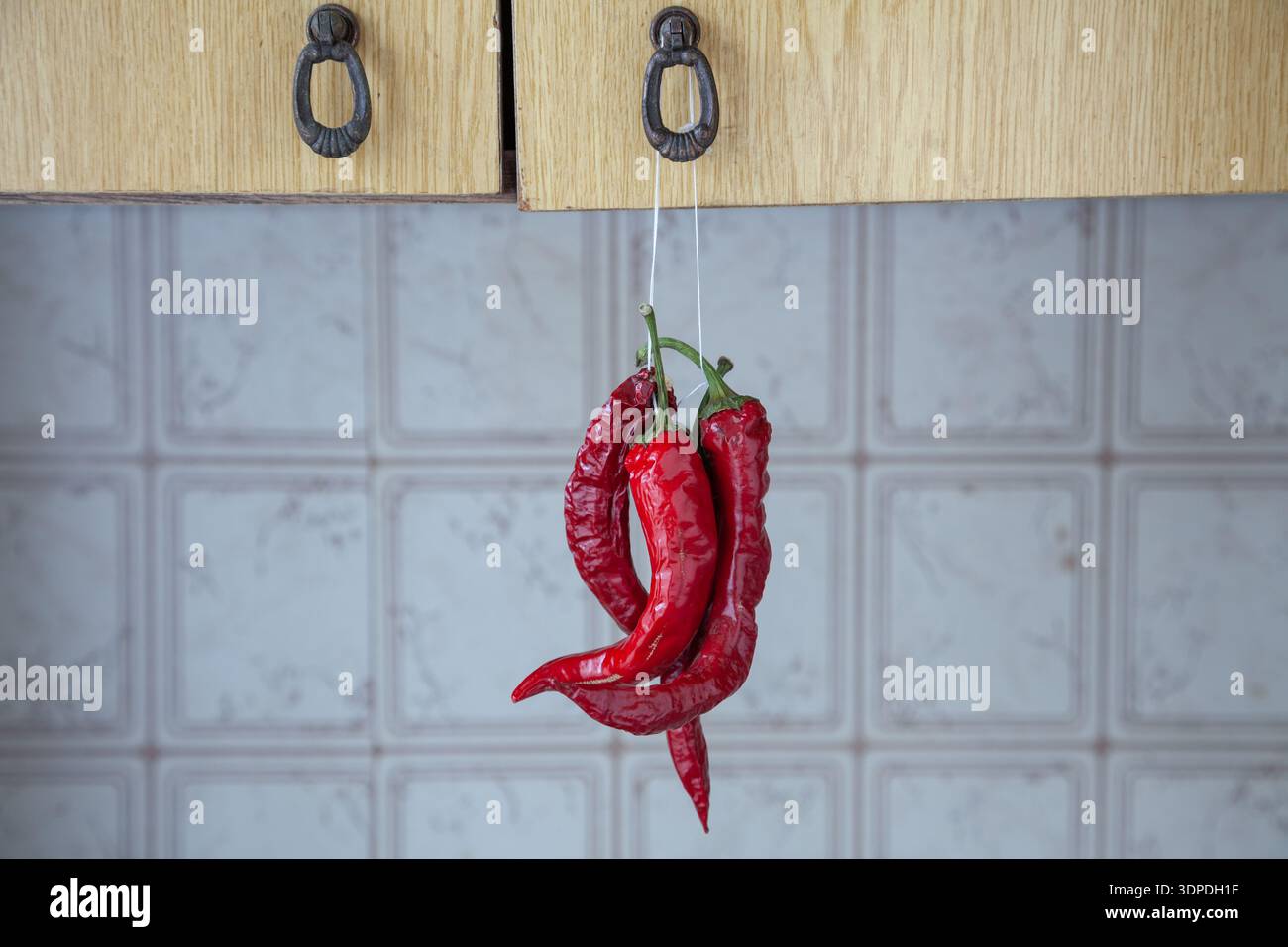 Piments rouges suspendus à une armoire de cuisine Banque D'Images