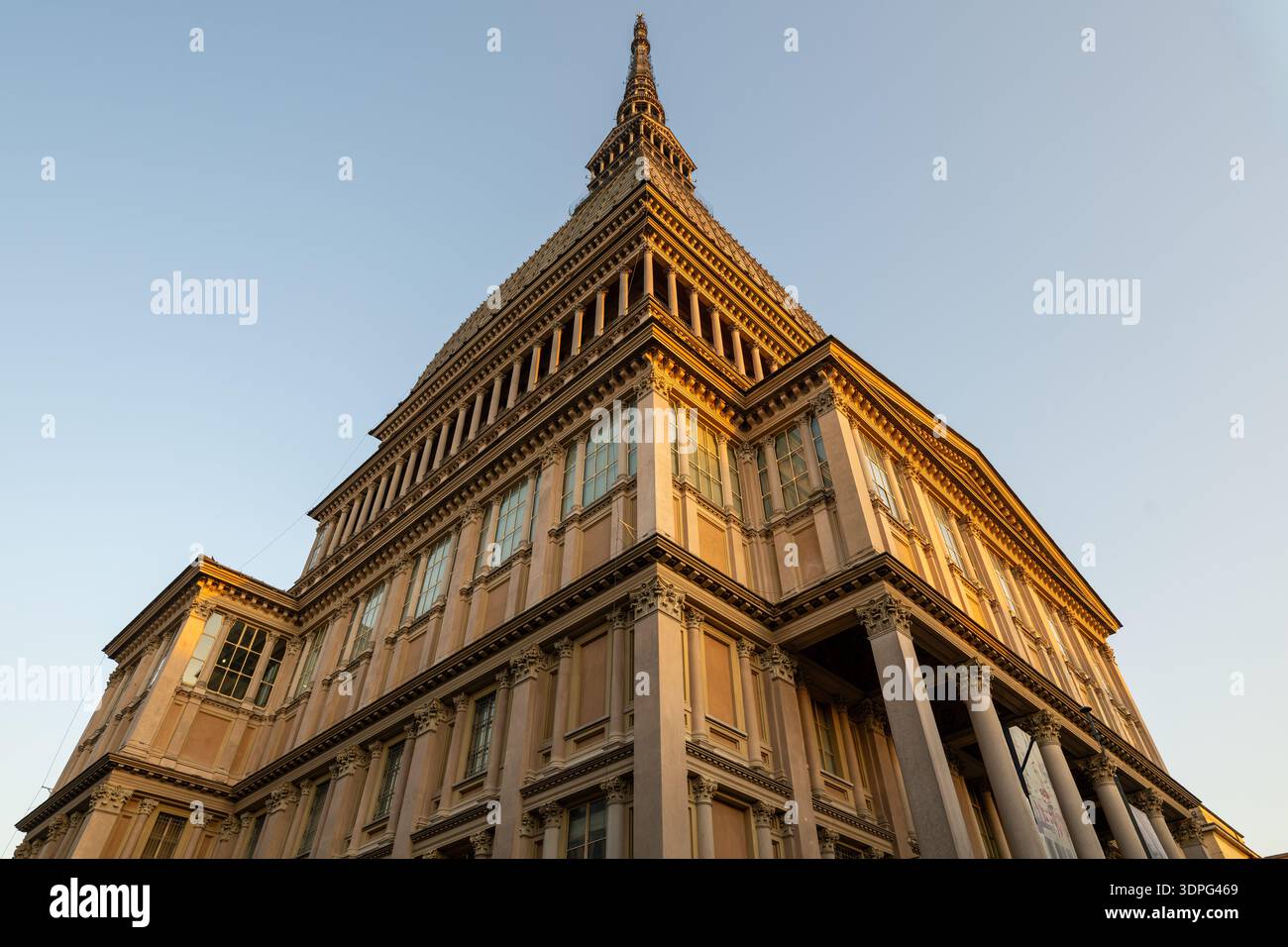 Vue en bas angle de la mole Antonelliana du XIXe siècle, monument néo-classique de Turin, illuminé par la lumière chaude du coucher de soleil sur ciel dégagé. Banque D'Images