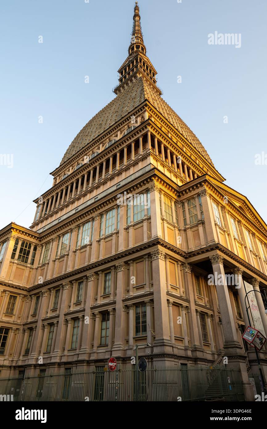 Vue en bas angle de la mole Antonelliana du XIXe siècle à Turin, montrant son dôme en briques et en pierre et sa flèche montante au coucher du soleil. Banque D'Images