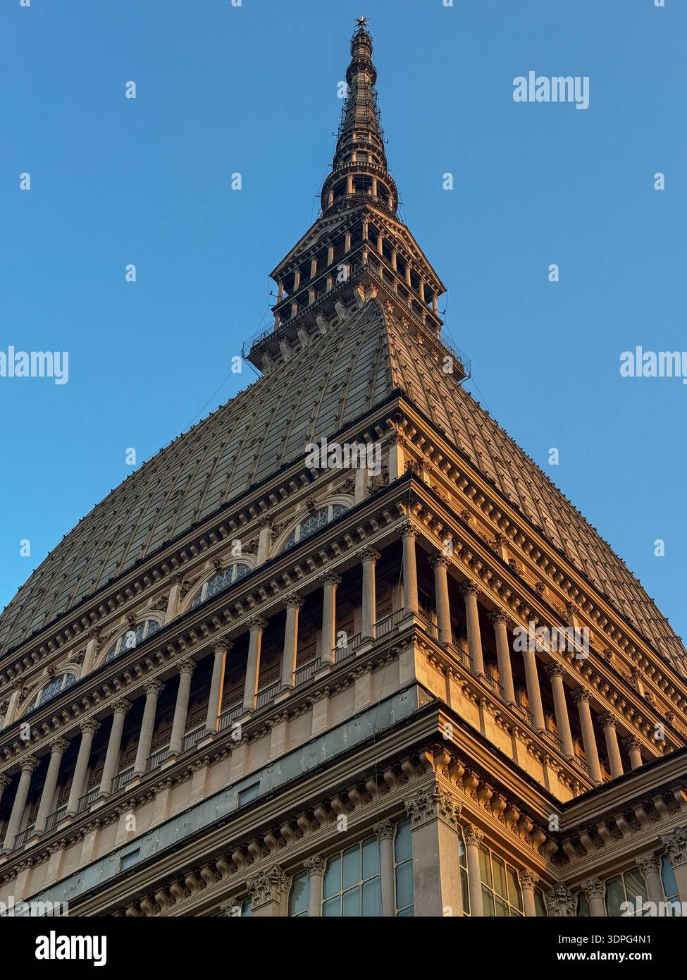 Vue sous-jacente du dôme et de la flèche de la mole Antonelliana datant du XIXe siècle à Turin, montrant des maçonneries éclectiques, des pilastres et des fenêtres dans la lumière chaude du soir. Banque D'Images