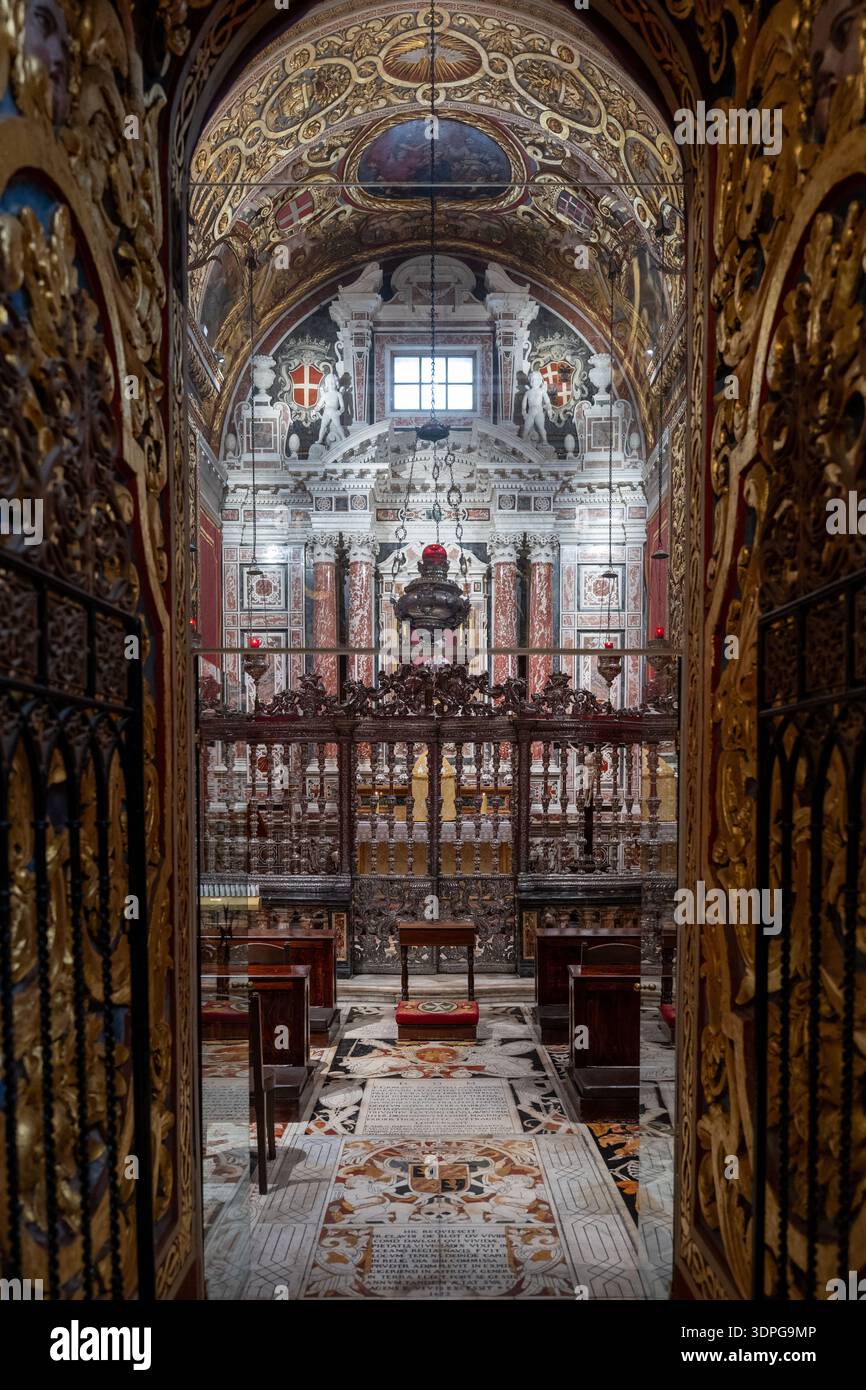 Valletta, Malte - 13 août 2025 : vue à travers des portes sculptées dorées dans la Co-cathédrale John, la Valette : nef baroque avec plancher de tombeau en marbre, forgé-ir Banque D'Images