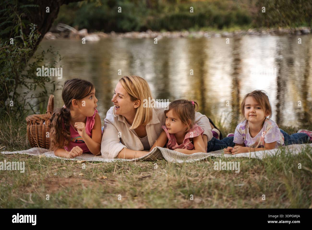 Mère et filles profitant d'un pique-nique au bord de la rivière Banque D'Images