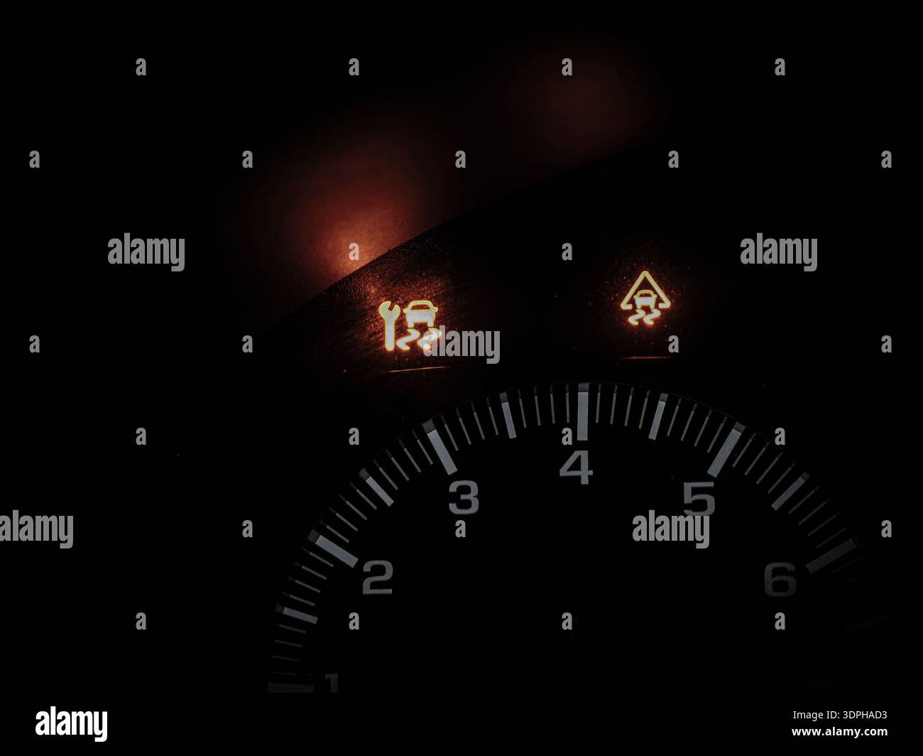 Tableau de bord de la voiture la nuit montrant les témoins d'avertissement de contrôle de traction et de contrôle de stabilité allumés sur le tableau de bord Banque D'Images