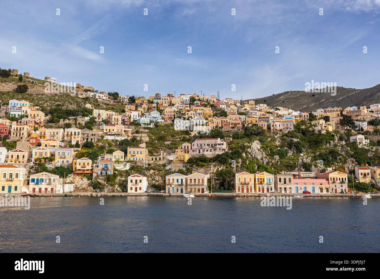 Bâtiments colorés sur une colline dans la ville idyllique de Symi au bord de la mer Égée sur l'île de Symi (Simi, Syme) en Grèce par une journée ensoleillée. Banque D'Images