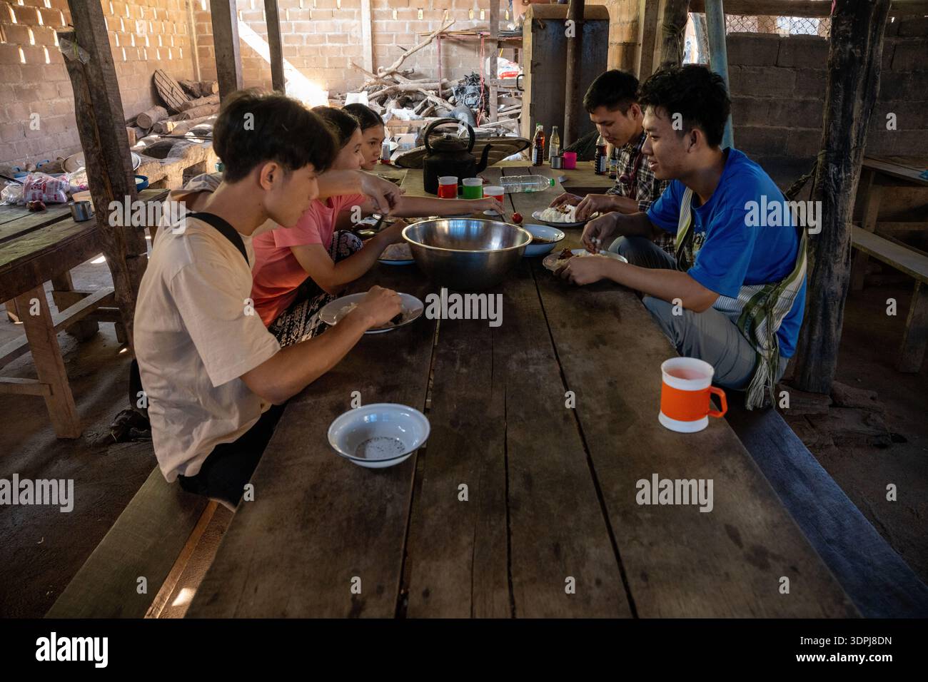 Les étudiants partagent un déjeuner simple et commun à une table rustique en bois dans le camp de réfugiés de Mae la, province de Tak, Thaïlande. Banque D'Images