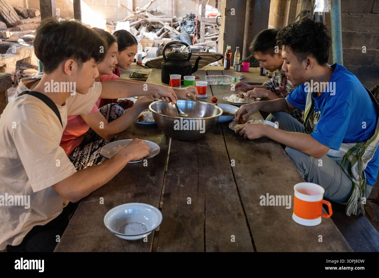 Les élèves partagent un déjeuner commun à une table rustique en bois dans une école biblique du camp de réfugiés de Mae la, province de Tak, Thaïlande. Banque D'Images