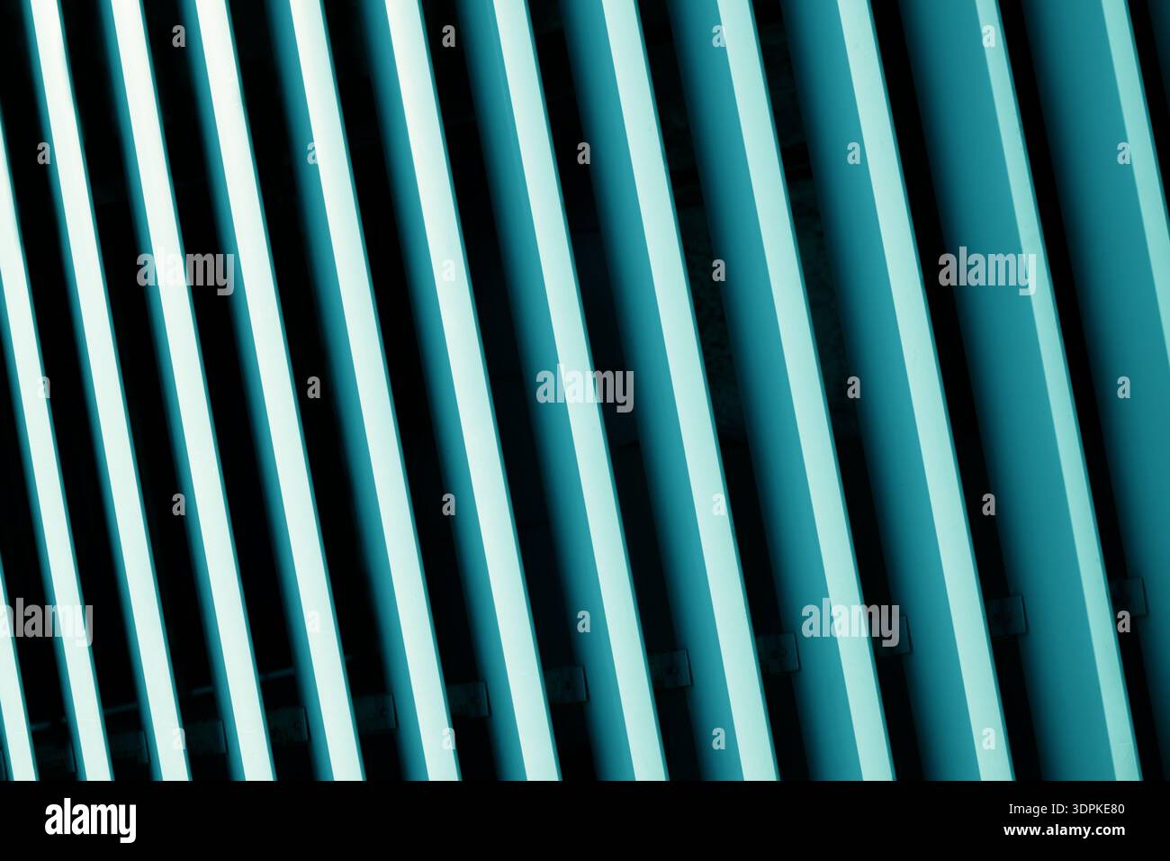 Une vue abstraite en gros plan de lignes parallèles sarcelle et noires inclinées en diagonale, formant un motif géométrique saisissant avec un contraste et une ombre forts Banque D'Images