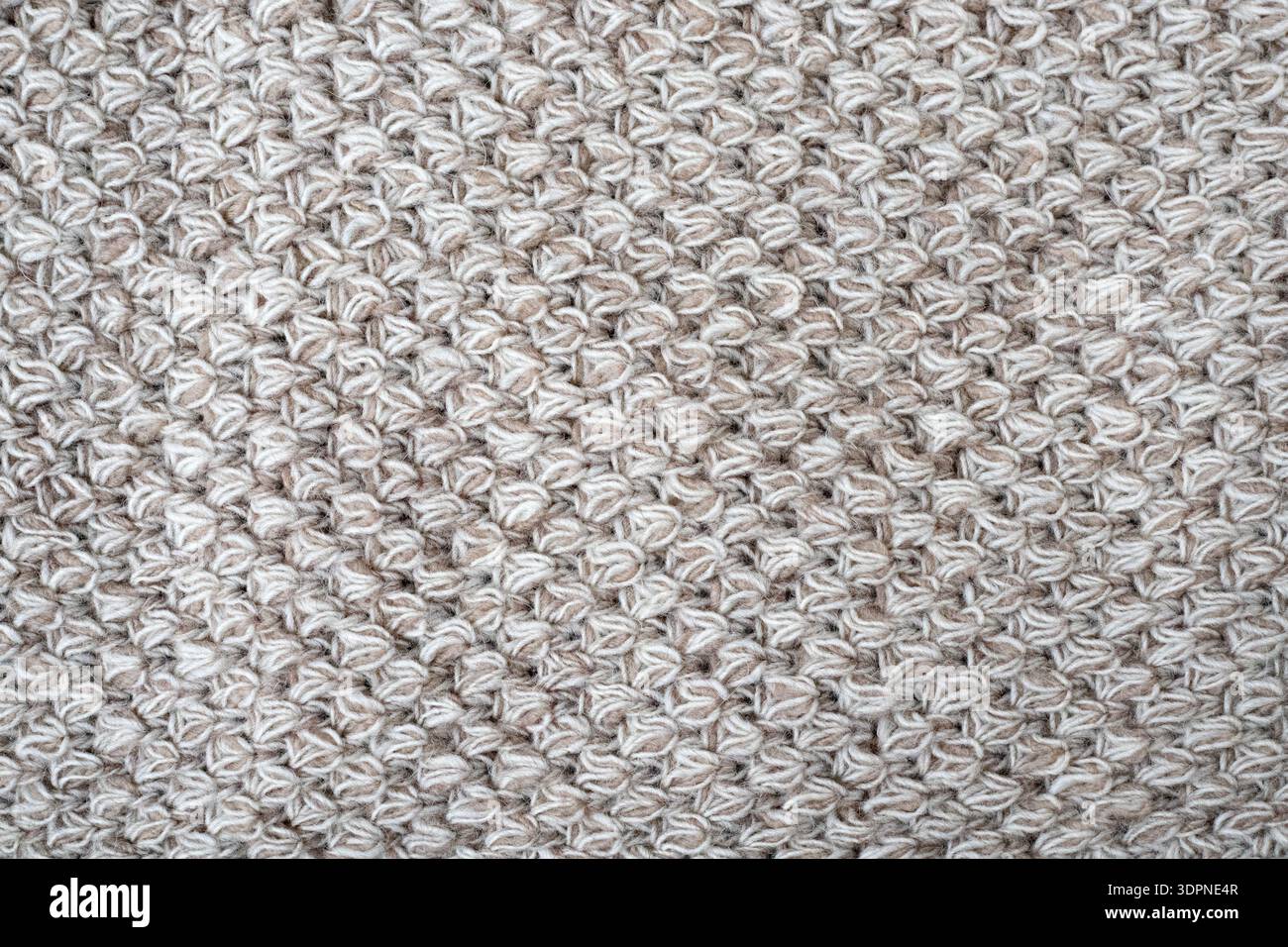 Couverture grise en laine au crochet comme fond. Texture macro tricotée, gros plan de la surface avant crochetée beige, texture de laine de laine, fron tricoté Banque D'Images