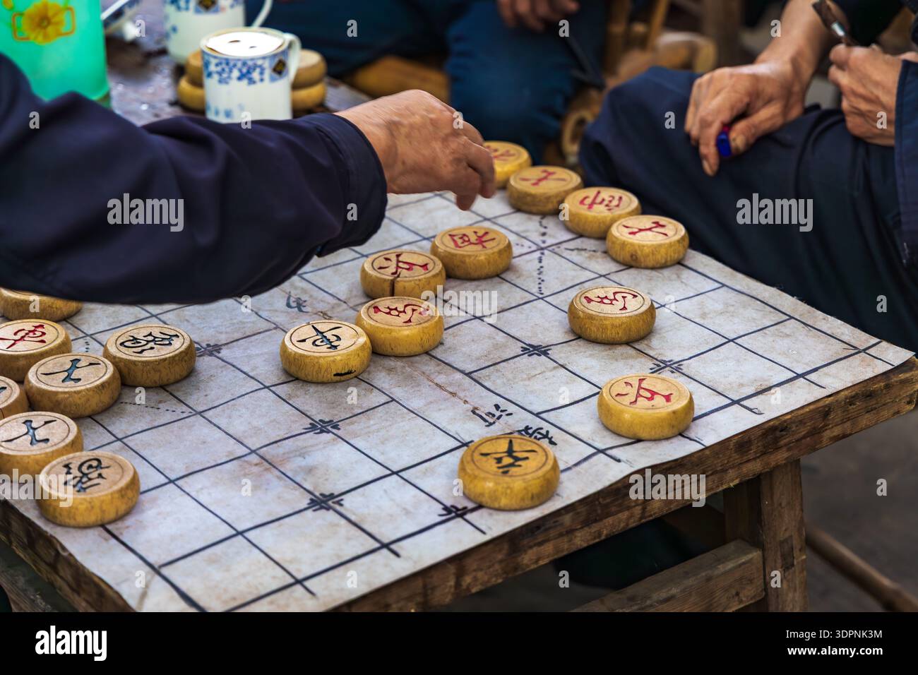 Les échecs chinois sont joués en plein air devant une maison de thé traditionnelle (sur les pièces d'échecs sont des caractères chinois pour roi, conseillers, général, soldats, Banque D'Images
