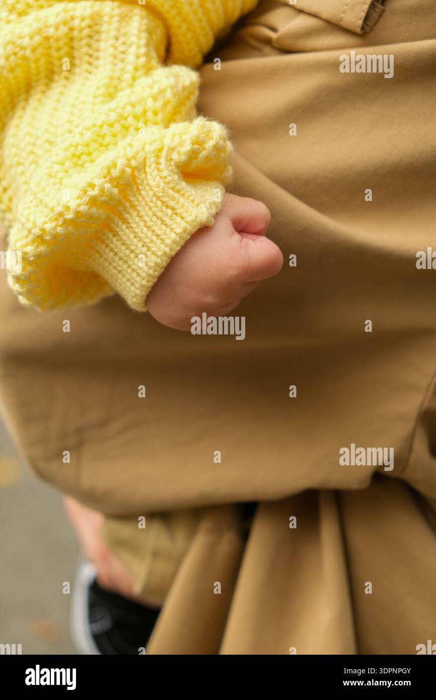 Gros plan de la main de l'enfant en pull jaune Banque D'Images
